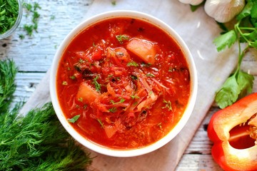 Ukrainian and Russian cuisine, red borsch. Tomato soup. Vegetable borscht made from tomato, bell pepper, parsley, onions, potatoes, carrots, cabbage and beets. Food on a wooden background. Food in a w
