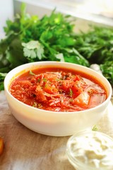 Ukrainian and Russian cuisine, red borsch. Tomato soup. Vegetable borscht made from tomato, bell pepper, parsley, onions, potatoes, carrots, cabbage and beets. Food on a wooden background.