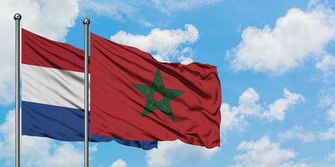 Netherlands and Morocco flag waving in the wind against white cloudy blue sky together. Diplomacy concept, international relations.