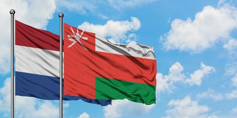 Netherlands and Oman flag waving in the wind against white cloudy blue sky together. Diplomacy concept, international relations.