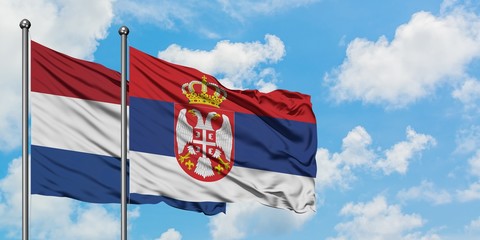 Netherlands and Serbia flag waving in the wind against white cloudy blue sky together. Diplomacy concept, international relations.