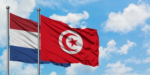 Netherlands and Tunisia flag waving in the wind against white cloudy blue sky together. Diplomacy concept, international relations.
