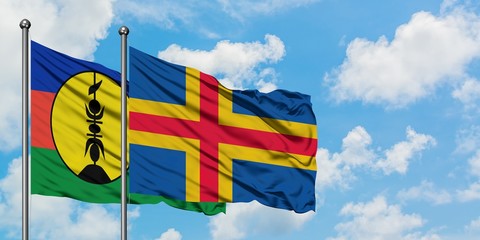 New Caledonia and Aland Islands flag waving in the wind against white cloudy blue sky together. Diplomacy concept, international relations.