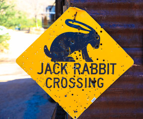 Rabbit crossing road sign at route 66 with bullet holes