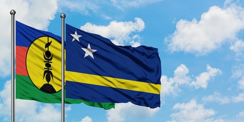 New Caledonia and Curacao flag waving in the wind against white cloudy blue sky together. Diplomacy concept, international relations.