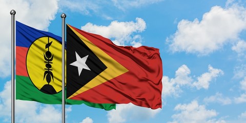 New Caledonia and East Timor flag waving in the wind against white cloudy blue sky together. Diplomacy concept, international relations.