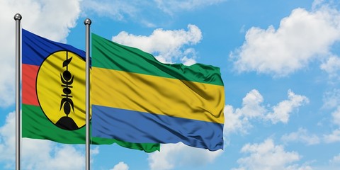 New Caledonia and Gabon flag waving in the wind against white cloudy blue sky together. Diplomacy concept, international relations.