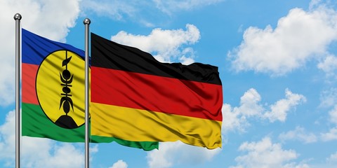 New Caledonia and Germany flag waving in the wind against white cloudy blue sky together. Diplomacy concept, international relations.