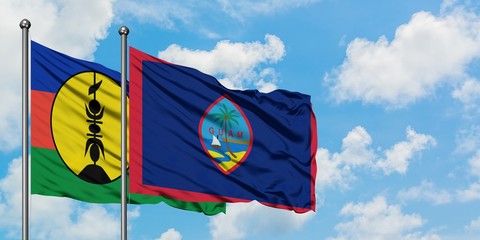 New Caledonia and Guam flag waving in the wind against white cloudy blue sky together. Diplomacy concept, international relations.