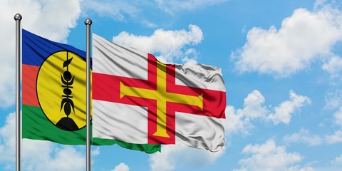 New Caledonia and Guernsey flag waving in the wind against white cloudy blue sky together. Diplomacy concept, international relations.