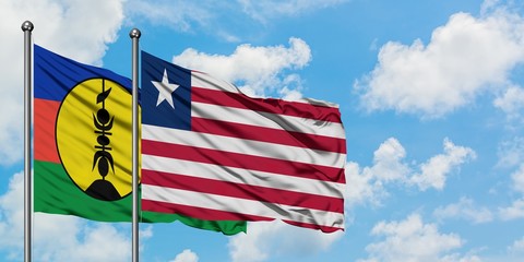 New Caledonia and Liberia flag waving in the wind against white cloudy blue sky together. Diplomacy concept, international relations.