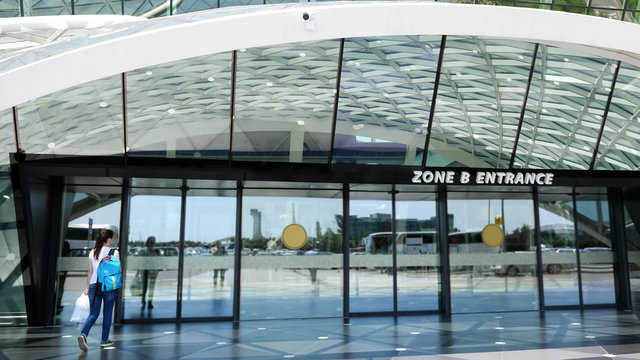 View at the entrance of airport with woman entering the door. New modern airport terminal.