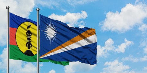 New Caledonia and Marshall Islands flag waving in the wind against white cloudy blue sky together. Diplomacy concept, international relations.