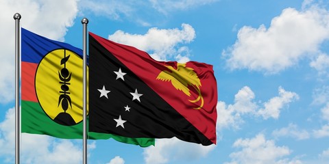 New Caledonia and Papua New Guinea flag waving in the wind against white cloudy blue sky together. Diplomacy concept, international relations.