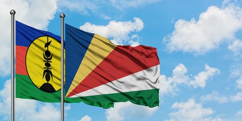 New Caledonia and Seychelles flag waving in the wind against white cloudy blue sky together. Diplomacy concept, international relations.
