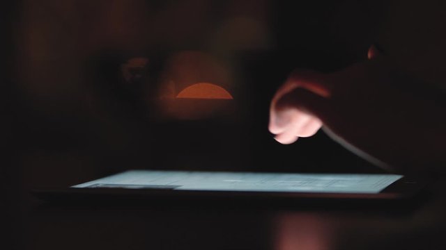 Woman using digital tablet at night. hands touching tablet touchscreen online shopping