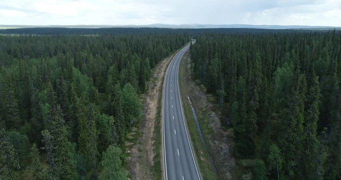 Country road, 4k aerial, drone shot. Flying over cars on a road.  Beautiful forest curving road, on a cloudy day. Lappi, Finland