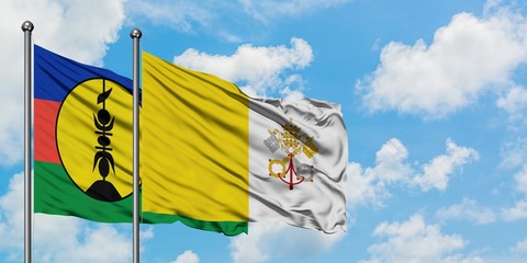 New Caledonia and Vatican City flag waving in the wind against white cloudy blue sky together. Diplomacy concept, international relations.