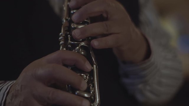 A CLOSE UP of a man playing a clarinet. HANDHELD.