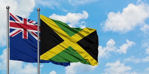 New Zealand and Jamaica flag waving in the wind against white cloudy blue sky together. Diplomacy concept, international relations.