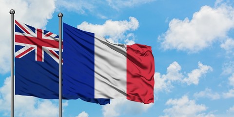New Zealand and Reunion flag waving in the wind against white cloudy blue sky together. Diplomacy concept, international relations.