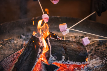 Selective focus, toasting a marshmallow over an open flame at Christmas market winter wonderland in London
