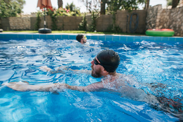 man swims in pool near villa