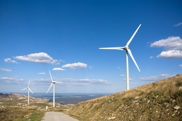 View of a wind turbines on top of mountains, blue sky as background