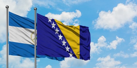 Nicaragua and Bosnia Herzegovina flag waving in the wind against white cloudy blue sky together. Diplomacy concept, international relations.