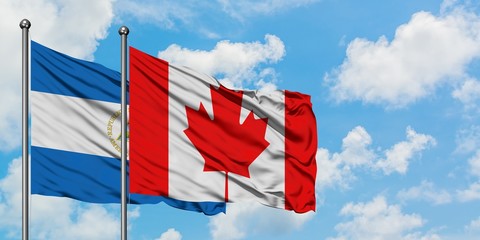 Nicaragua and Canada flag waving in the wind against white cloudy blue sky together. Diplomacy concept, international relations.