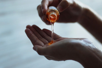 Woman pouring some orange shower gel over her hand.