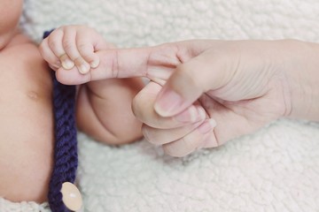 Hand of sleeping Newborn baby finger in the hand of parent mother on the bed. happy Love family healthcare and medical body part father day concept.