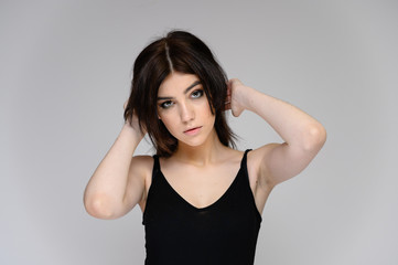 Close-up portrait of a young pretty girl student with long black hair, on a white background. He stands right in front of the camera, showing his hands in different poses with different emotions.