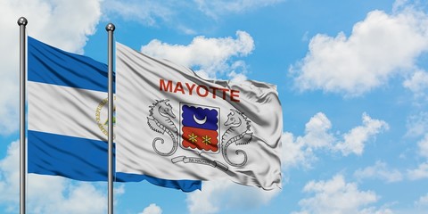 Nicaragua and Mayotte flag waving in the wind against white cloudy blue sky together. Diplomacy concept, international relations.