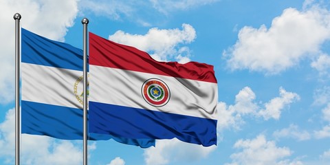 Nicaragua and Paraguay flag waving in the wind against white cloudy blue sky together. Diplomacy concept, international relations.