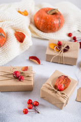 Autumn gifts with fallen leaves. Presents for Thanksgiving day wrapped in craft paper in rustic style with natural materials. Cozy autumn