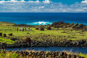Group of unrecognizable tourists visit ruined moai platform