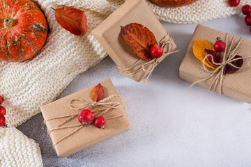 Autumn gifts with fallen leaves. Presents for Thanksgiving day wrapped in craft paper in rustic style with natural materials. Cozy autumn, copy space