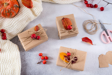 Fototapeta na wymiar Presents for Thanksgiving day wrapped in craft paper in rustic style with natural materials. Autumn gifts with fallen leaves. Cozy autumn, eco style. Top view