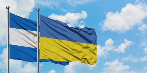Nicaragua and Ukraine flag waving in the wind against white cloudy blue sky together. Diplomacy concept, international relations.