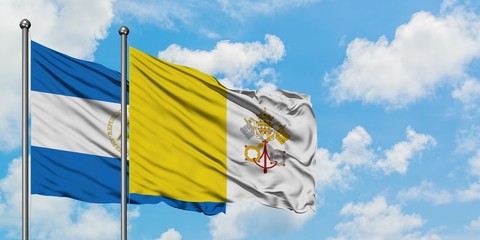 Nicaragua and Vatican City flag waving in the wind against white cloudy blue sky together. Diplomacy concept, international relations.