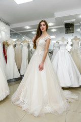 Naklejka premium Young and tiny bride in wedding dress in salon