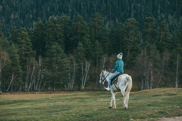 Teen girl riding a horse on meadow