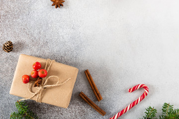 Christmas gift box. Christmas handmade present in craft paper, fir branches and cones on gray concrete background. Flat lay with copy space. Cozy winter