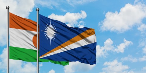 Niger and Marshall Islands flag waving in the wind against white cloudy blue sky together. Diplomacy concept, international relations.