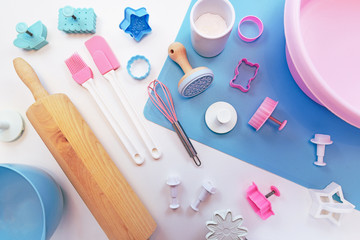 Top view flat lay with cute pink and blue baking utensils like baking mat, wooden rolling pin,...