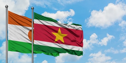 Niger and Suriname flag waving in the wind against white cloudy blue sky together. Diplomacy concept, international relations.