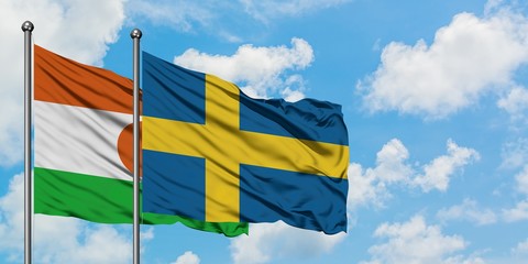 Niger and Sweden flag waving in the wind against white cloudy blue sky together. Diplomacy concept, international relations.