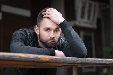 Pensive bearded young man outdoors in the afternoon in the city.