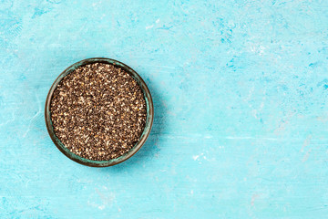 Chia seeds in a bowl, shot from the top on a blue background with a place for text